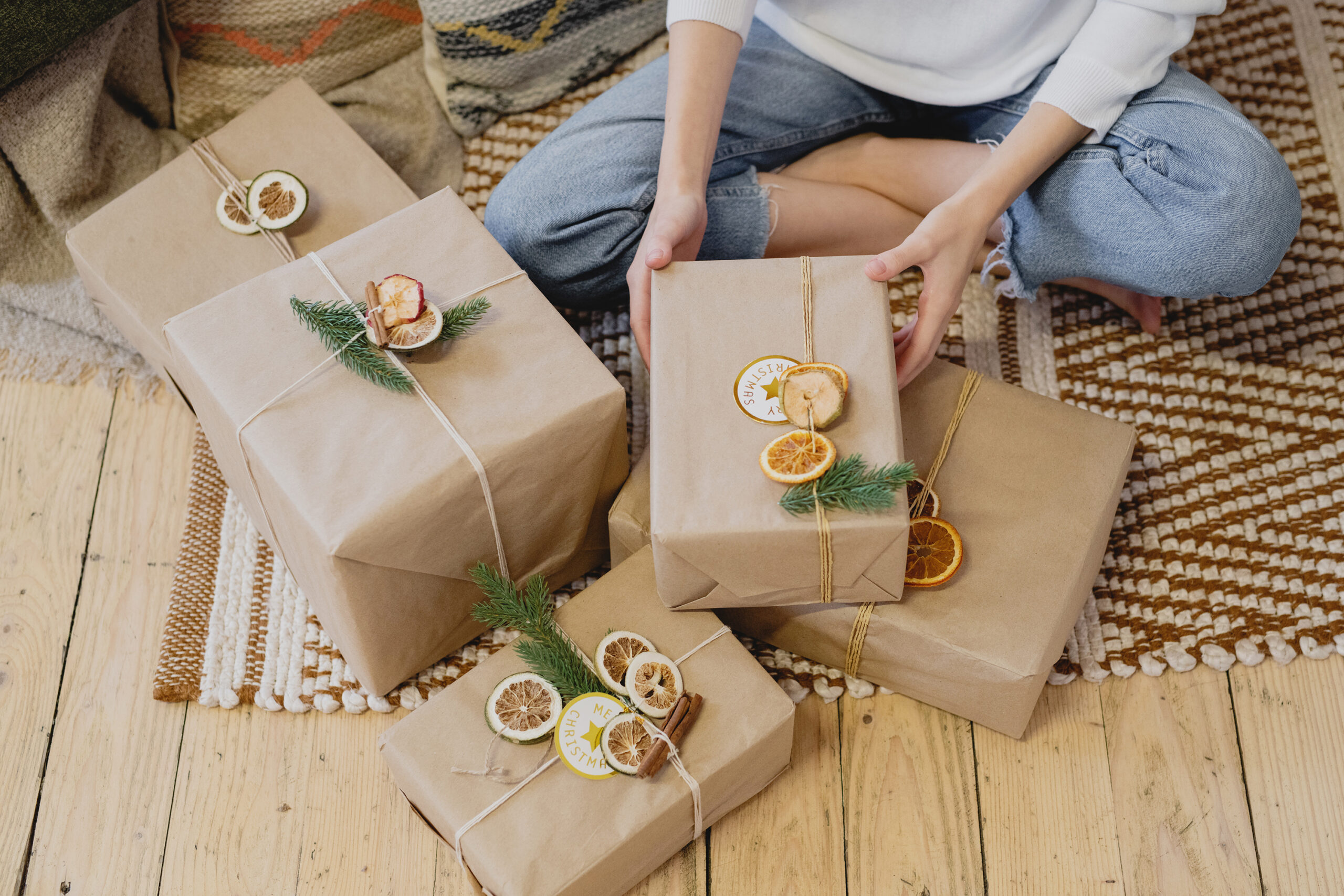 Photo of a person sitting cross-legged on the floor with various wrapped gifts.